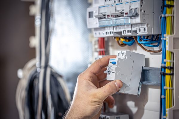 a-male-electrician-works-in-a-switchboard-with-an-SBYW32N