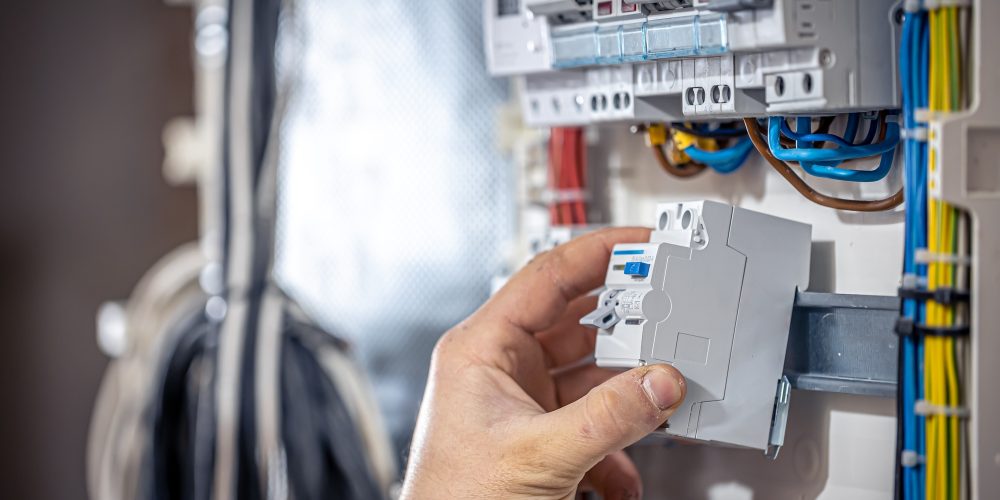 a-male-electrician-works-in-a-switchboard-with-an-SBYW32N
